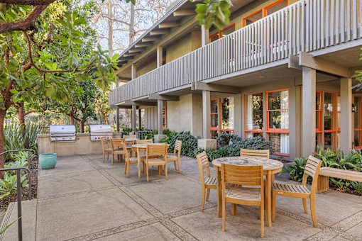 A patio with a table and chairs is surrounded by trees at The Aspens Fairhaven, Santa Ana, 92705