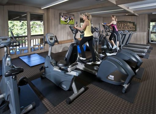 two women working out on exercise machines in a gym