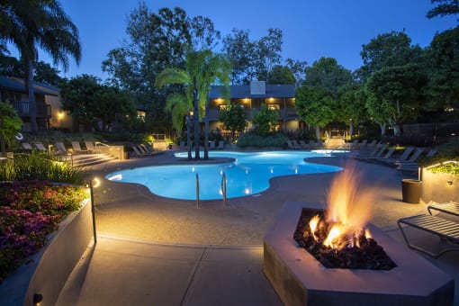 a swimming pool at night with a fire pit