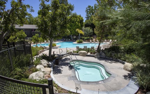 a pool and spa at an apartment community with trees