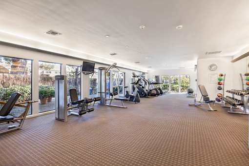 A spacious gym with a variety of equipment and a large mirror on the wall at The Aspens South Coast, California, 92504