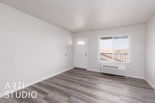 A room with a door and a window with blinds.