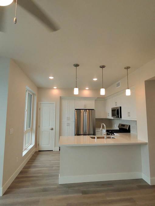 A kitchen with a white counter and a stainless steel refrigerator.