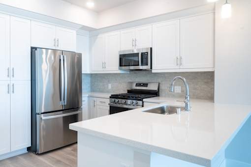 A modern kitchen with a stainless steel refrigerator and white cabinets.