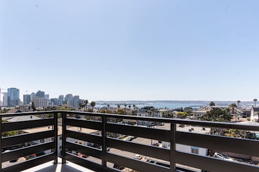 A balcony overlooks a cityscape and the ocean.