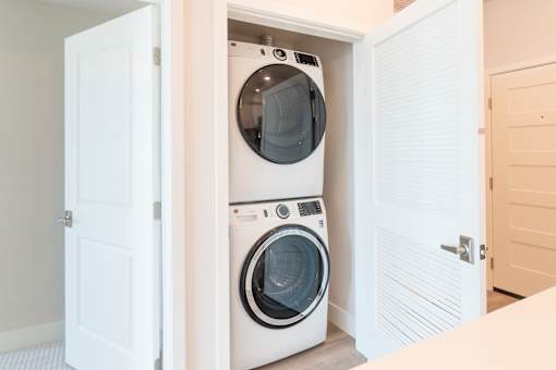 A white washing machine and dryer are built into a wall in a laundry room.