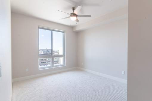 A room with a ceiling fan and a large window.