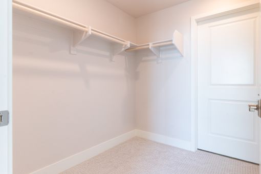 A white closet with a white door and a white shelf.