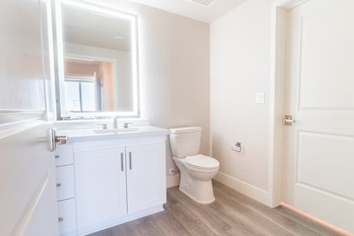 A white bathroom with a toilet, sink, and mirror.