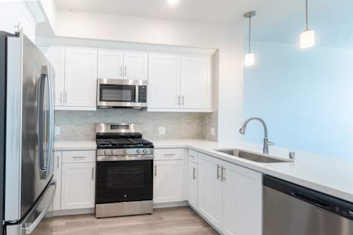A modern kitchen with white cabinets and stainless steel appliances.