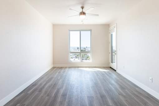 A room with a ceiling fan and a large window.