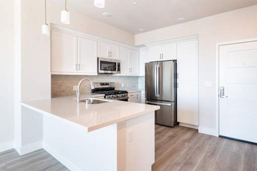 A modern kitchen with a stainless steel refrigerator and white cabinets.