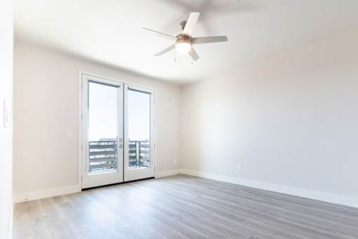 A room with a ceiling fan and sliding glass doors.