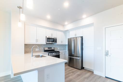 A modern kitchen with white cabinets and a stainless steel refrigerator.