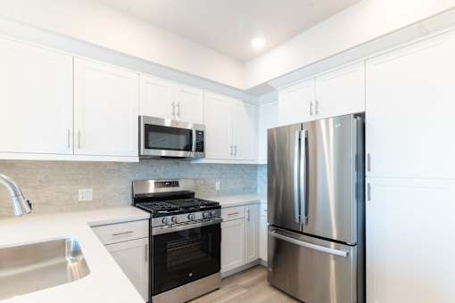 A modern kitchen with a stainless steel refrigerator, microwave, and oven.