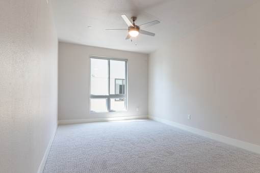 A room with a ceiling fan and a window.