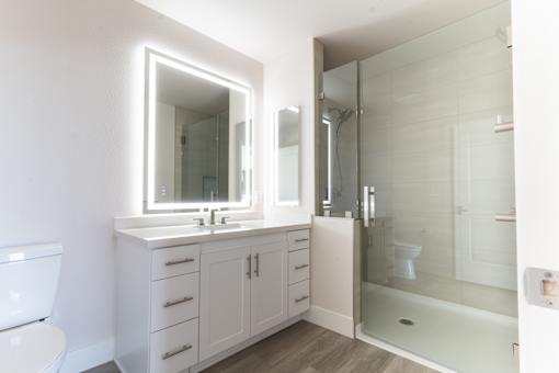 A white bathroom with a sink, mirror, and shower.
