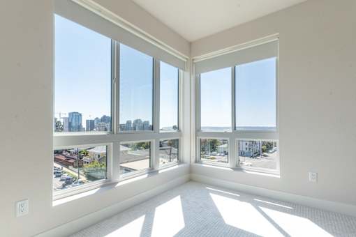 A sunny room with large windows overlooking a cityscape and beach.