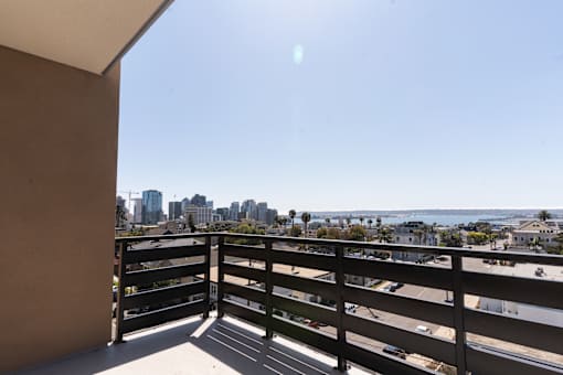 A balcony with a view of the city and the ocean.