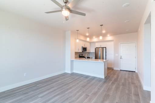 A spacious kitchen with a white counter and a ceiling fan.