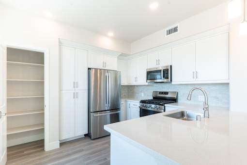 A kitchen with white cabinets and a stainless steel refrigerator.