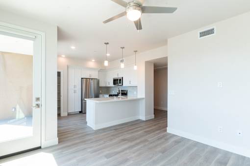 A modern kitchen with a bar area and a ceiling fan.