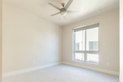 A room with a ceiling fan and a window.