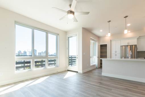 A spacious kitchen and living room with a large window overlooking the city.