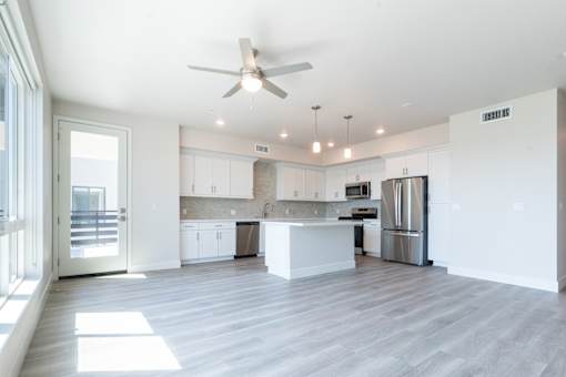 A spacious kitchen with a fan and stainless steel appliances.