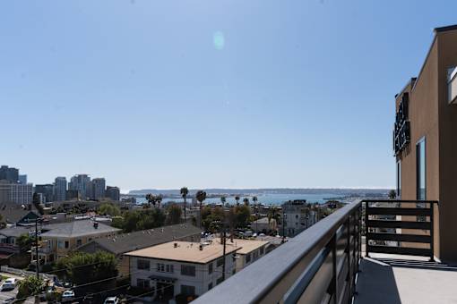 A balcony overlooks a residential area with a view of the ocean.