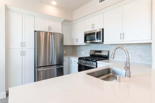 A kitchen with a stainless steel refrigerator, microwave, and oven.