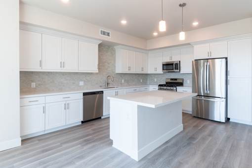 A kitchen with white cabinets and a large island.