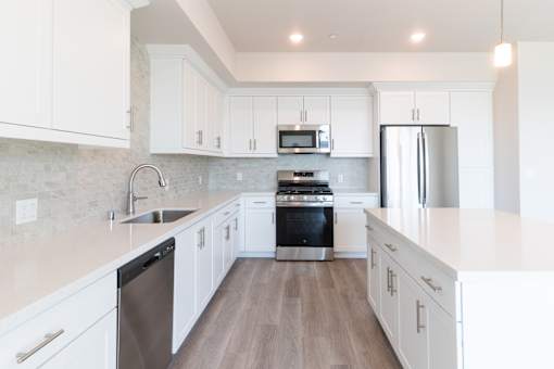 A modern kitchen with white cabinets and stainless steel appliances.