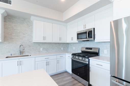 A modern kitchen with white cabinets and a stainless steel refrigerator.