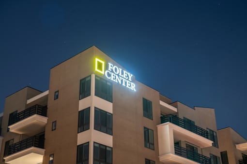 The Foley Center building is lit up at night.