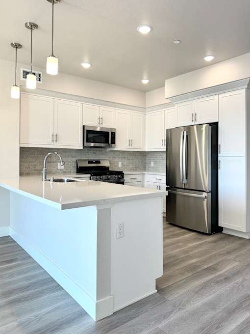 A modern kitchen with a white island and stainless steel appliances.