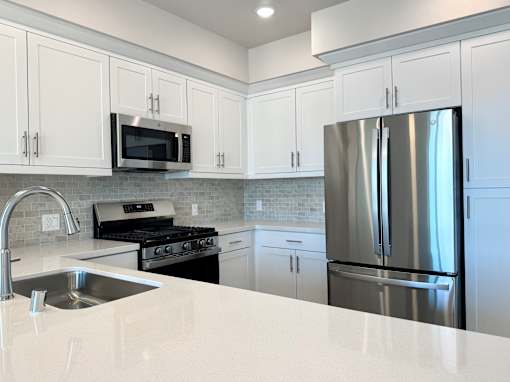 A modern kitchen with a stainless steel refrigerator, microwave, and oven.