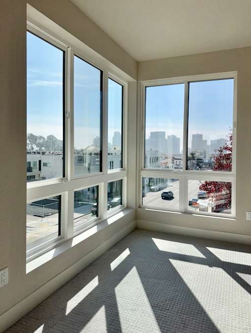 A sunny day in a room with large windows overlooking a cityscape.