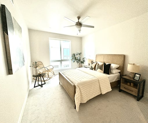 A bedroom with a large bed and a chair by the window.