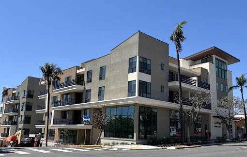 A modern building with a flat roof and balconies on the second floor.