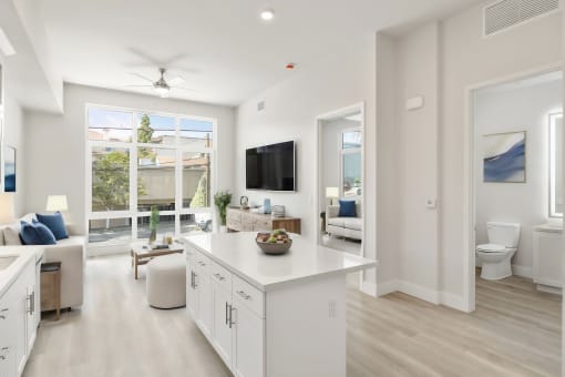 a white living room with a kitchen and a large window