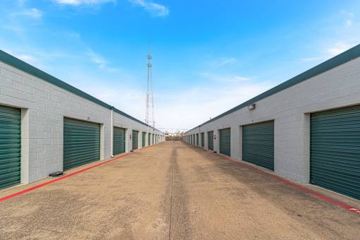 A long, straight road leads to a series of closed green garage doors.