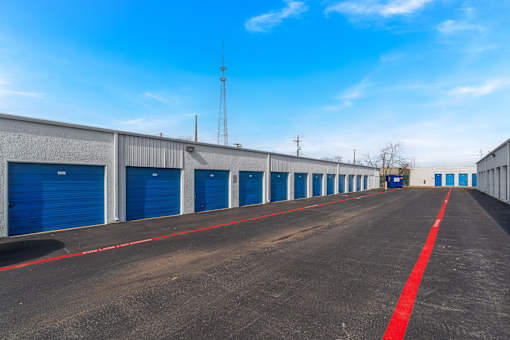 A long row of blue garage doors with a red line down the middle of the road.