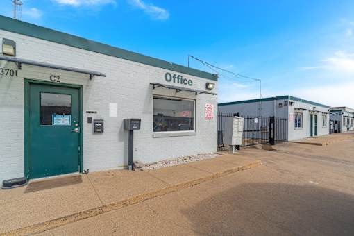 A white building with a green door and a sign that says "Office" on the front.