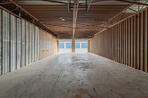 A long, empty room with a concrete floor and walls covered in wooden panels.