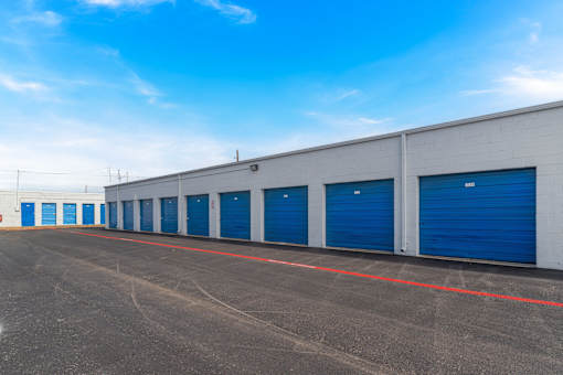 A long row of blue storage units in a parking lot.