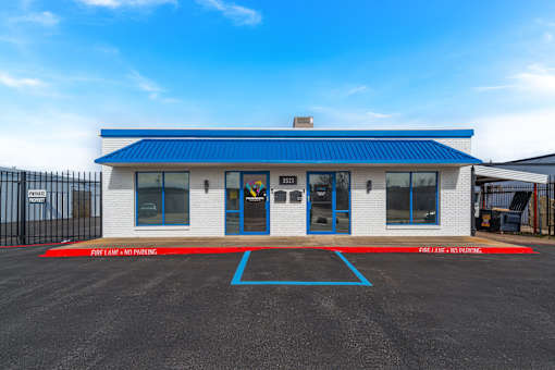A white building with a blue roof and a red and blue striped fire lane.