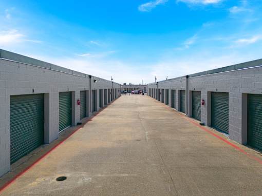 A long, empty parking lot with a clear blue sky above.