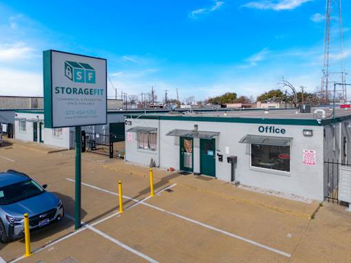 A blue car is parked in a parking lot in front of a building with a sign that says StorageFit.