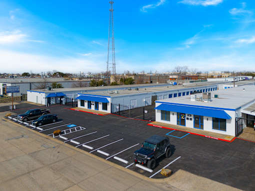A parking lot with a blue building and a tall tower in the background.